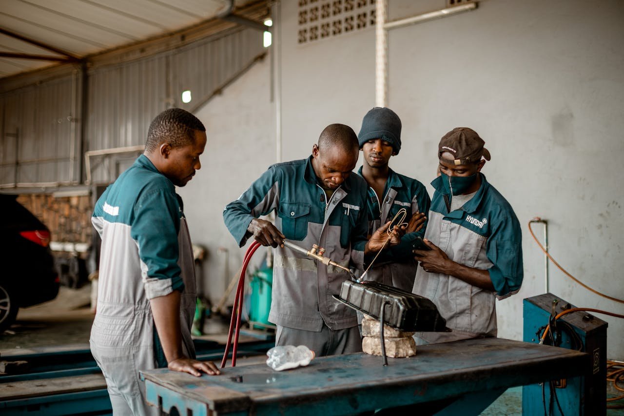 Skilled workers collaborating on metalwork in an industrial workshop setting.